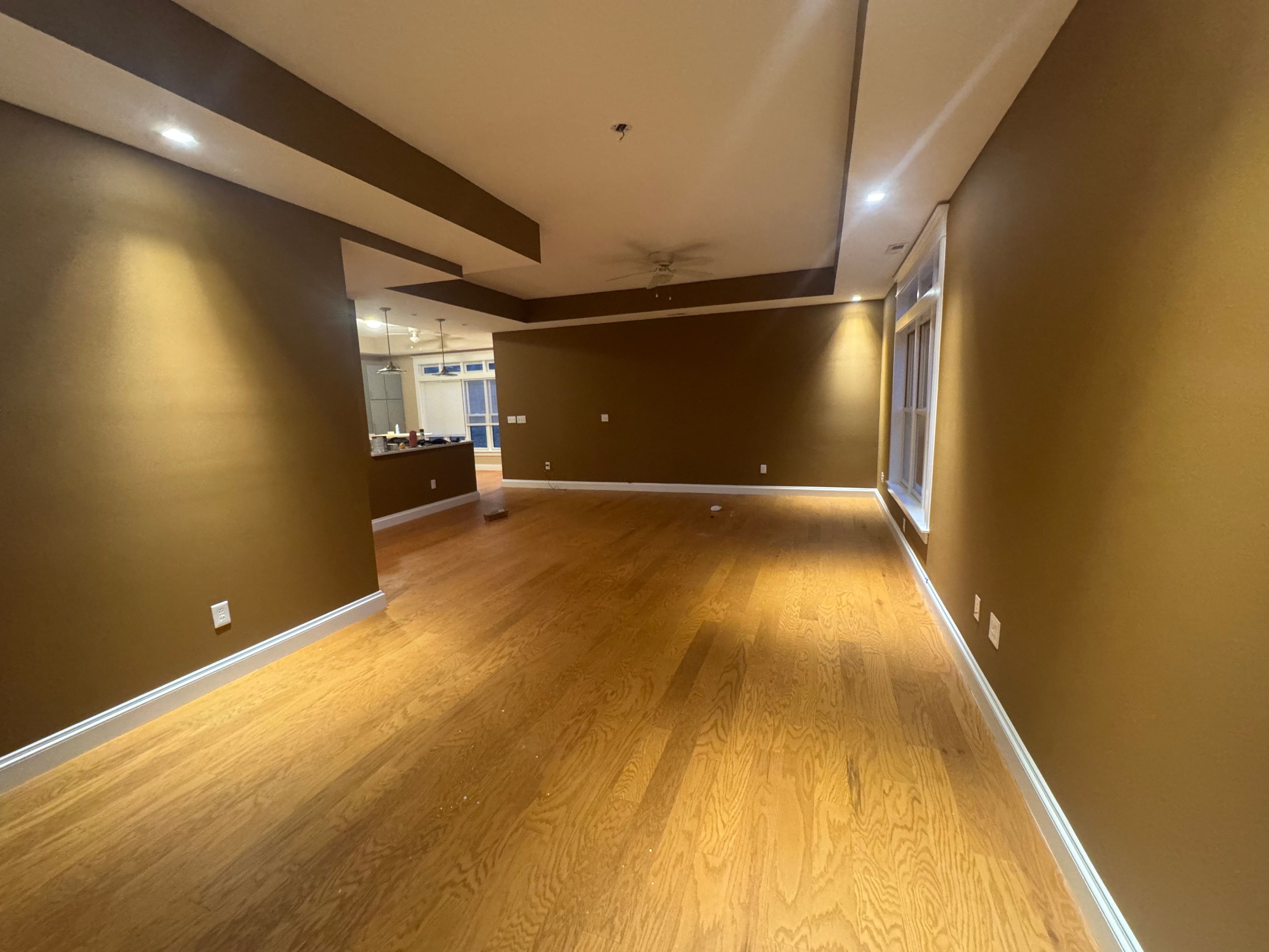 Spacious interior of a modern room with brown walls and hardwood flooring.