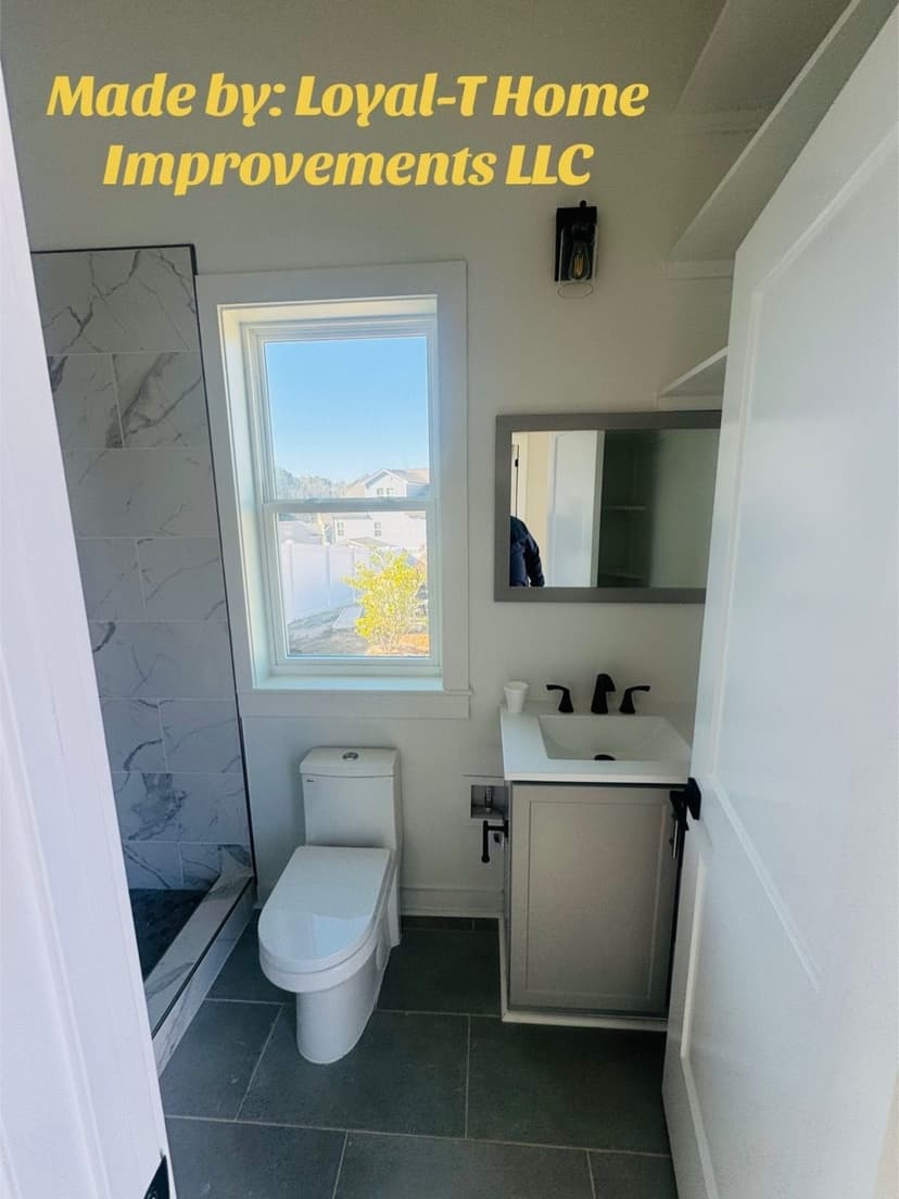 Modern bathroom with a toilet, sink, mirror, and natural light from a window.