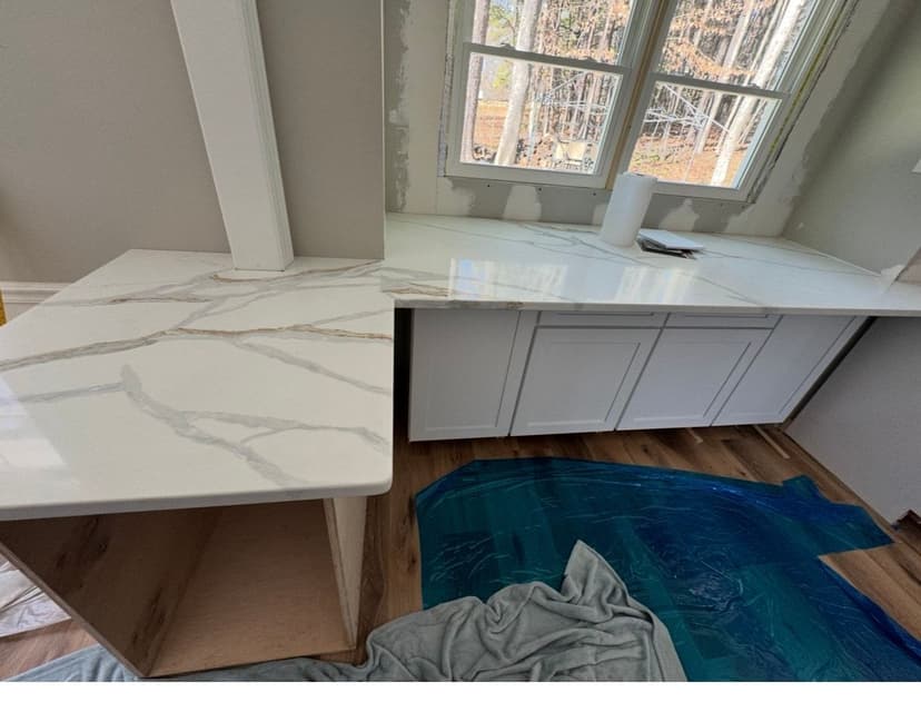 Modern kitchen countertops with white cabinetry and marble finish during installation.